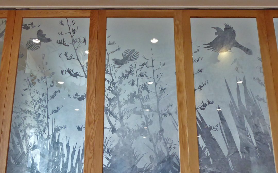 Detailed silhouette design of NZ native birds flying around a flax bush - on a window