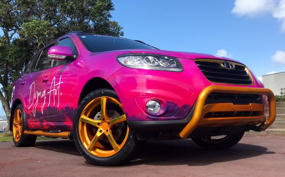 Dying Art company car wrapped in a bright pink livery