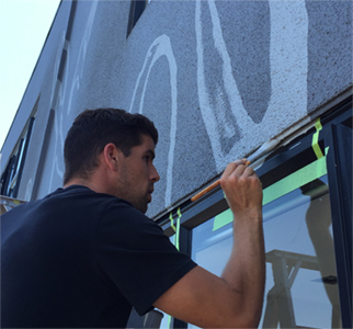 Hand painting a wall mural, with BIG team member using masking tape and a paintbrush