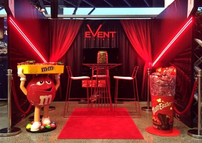Life sized M&M's display with red lighting and seating arrangement