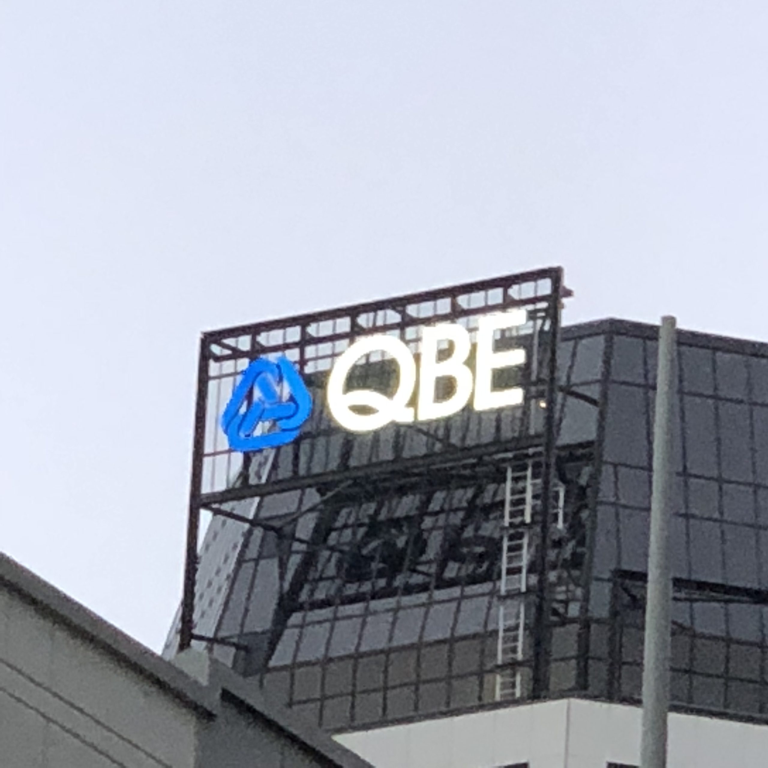 QBE light-up sign mounted to the top of high-rise building