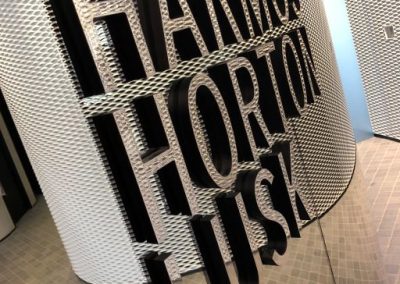 Mirrored 3D word display on wall, saying Harmos, Horton, and Lusk