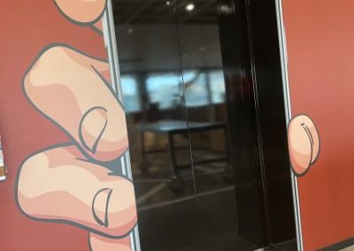 Wall art of cartoon hand holding a phone, with elevator entrance made to look like a phone